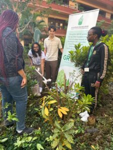 Huron Student looking at sign with plants in front of it in Kenya